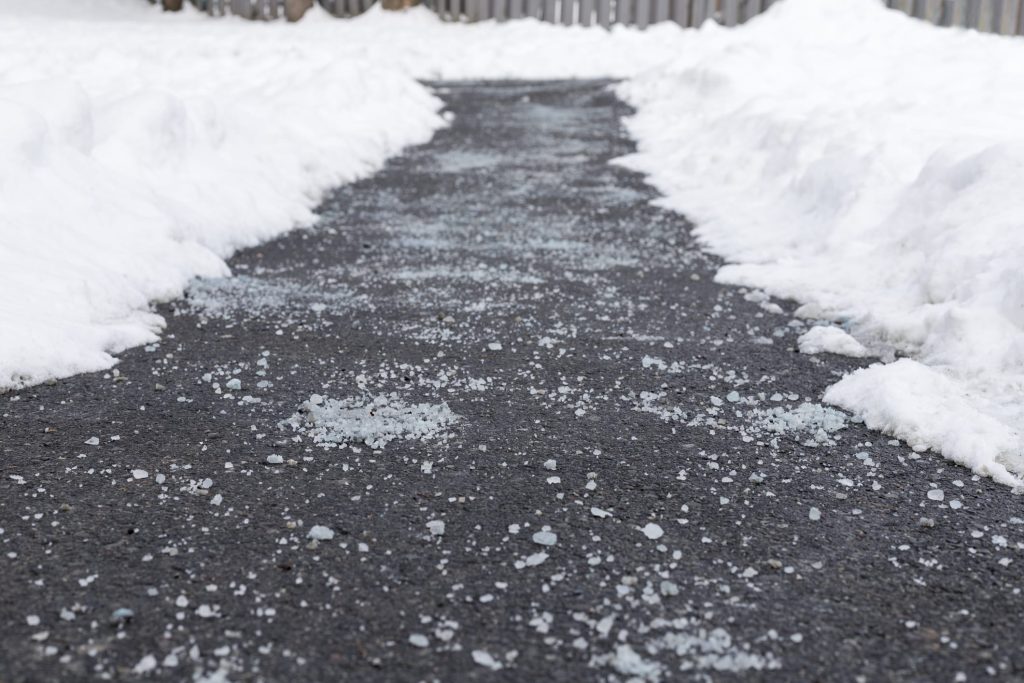 Salted asphalt sidewalk cleaned path with salt