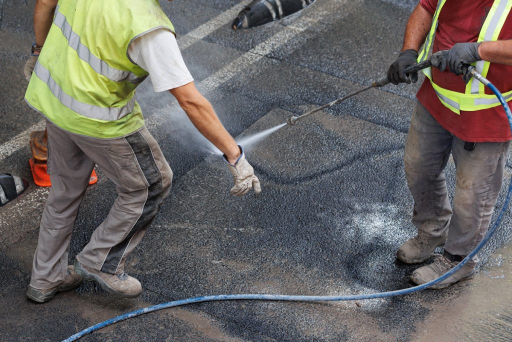 Professional crew powerwashing and removing oil stains from asphalt