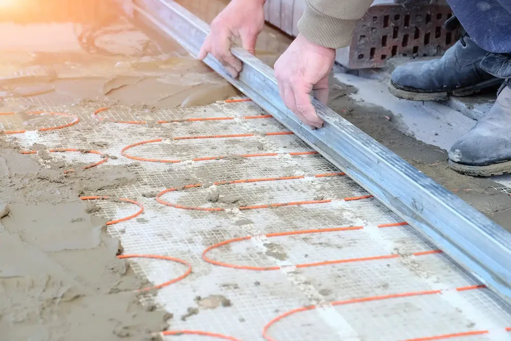 Electric heating cables being installed in a concrete driveway during radiant snow-melt system construction.