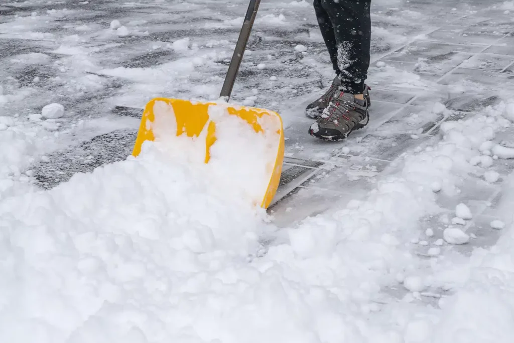 Person shoveling snow from a driveway during winter.